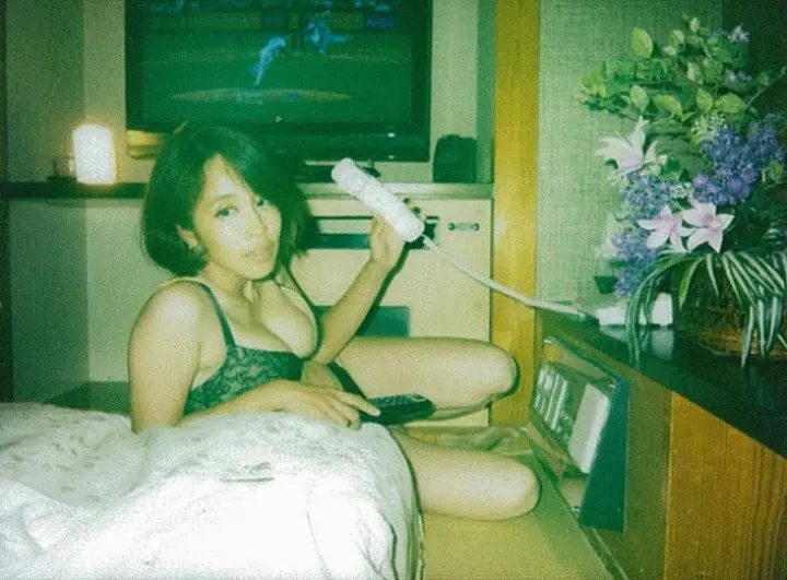 Woman in a hotel room lit by the TV — color film photograph by Marco Miraglia