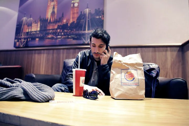 Marco Miraglia on the phone in a London Burger King, Big Ben on the wall behind him