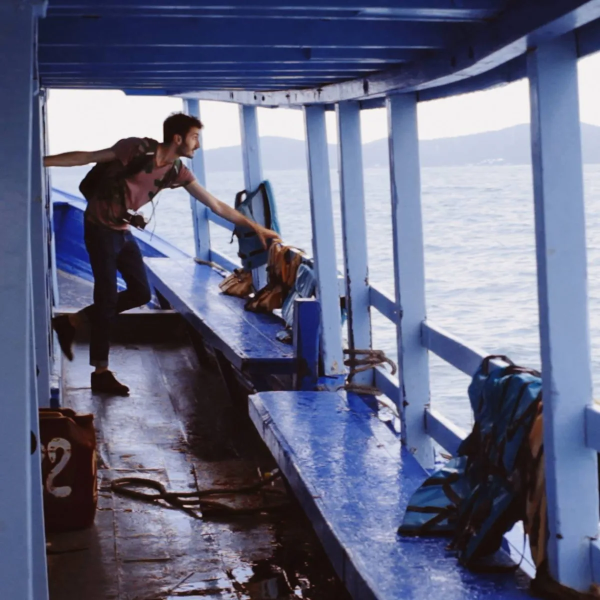 Marco Miraglia with a camera around his neck on a wooden boat in Thailand